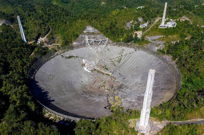 Aerial view of the former Arecibo Observatory radio telescope dish after its suspended platform collapsed.