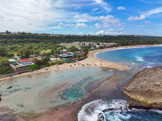 Curved beach, rocky shore, and clear water along the Isabela coast.