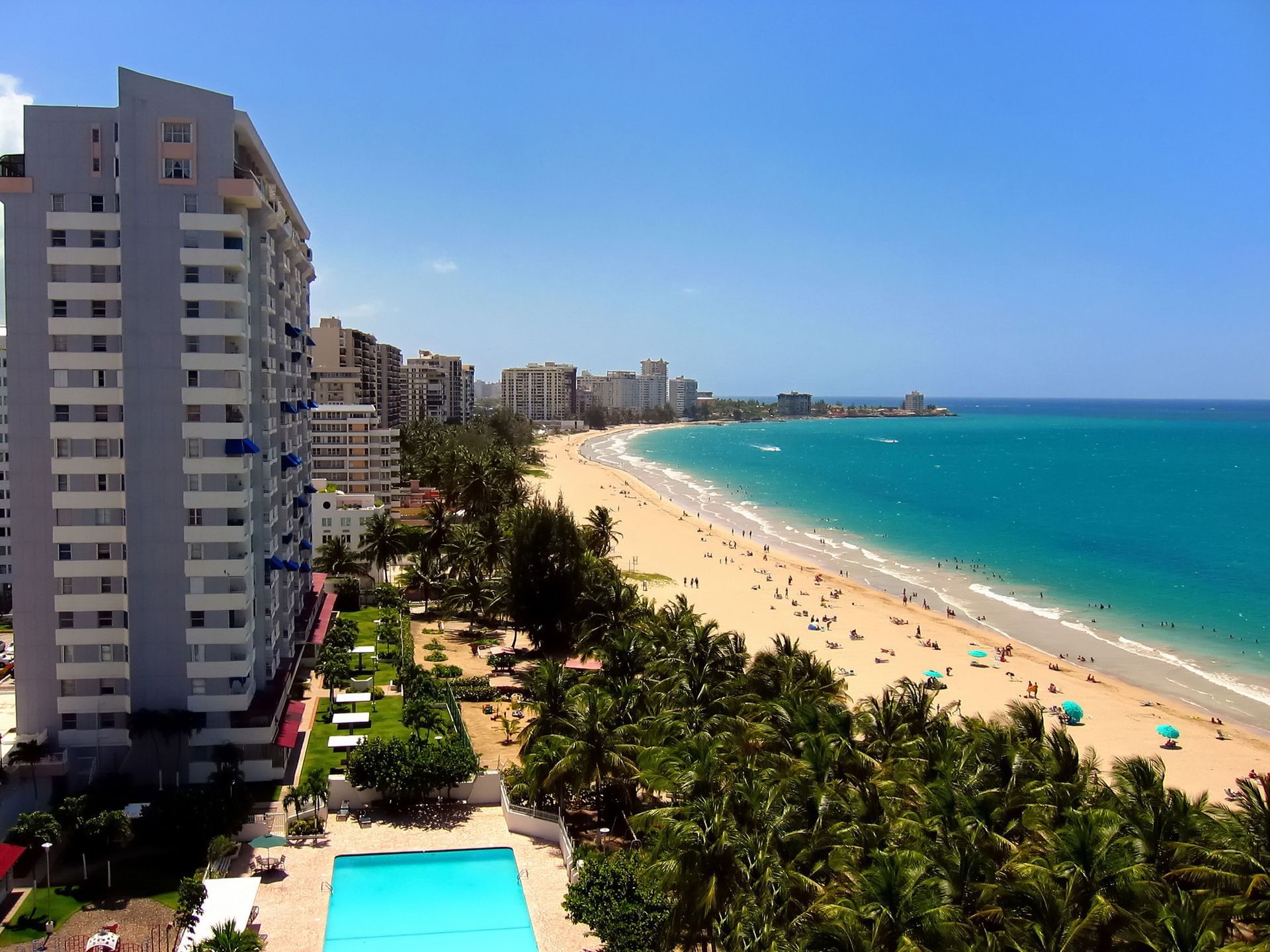 Beachfront condominium towers and turquoise water along Isla Verde in Carolina.