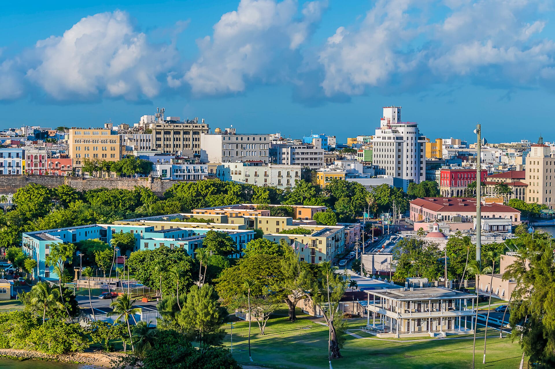 Metro-facing urban buildings and green civic areas connected to Guaynabo's market context.